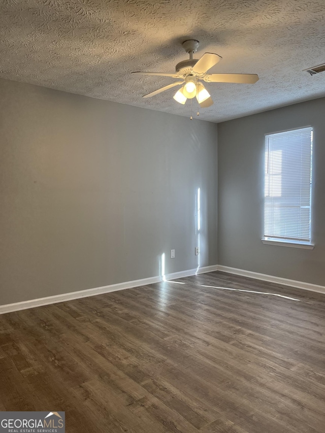 unfurnished room featuring visible vents, baseboards, and dark wood-style flooring