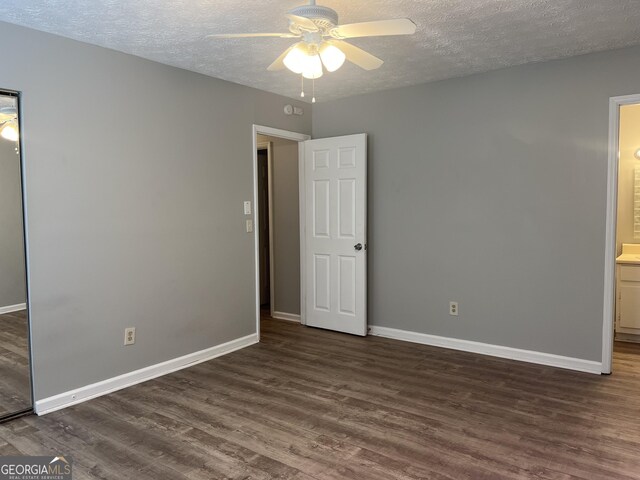 unfurnished bedroom with dark wood-style floors, baseboards, and a textured ceiling