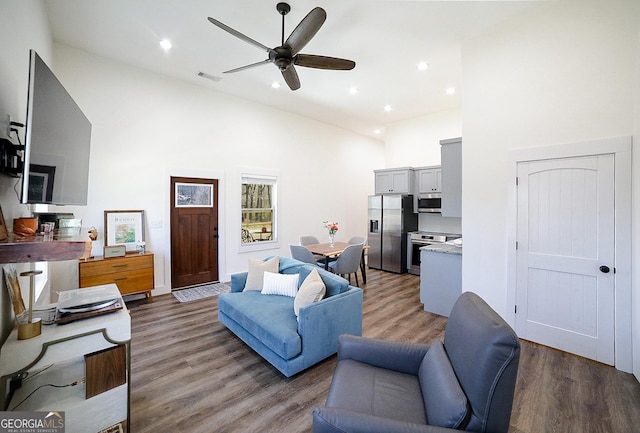 living area with light wood-type flooring, high vaulted ceiling, ceiling fan, and visible vents