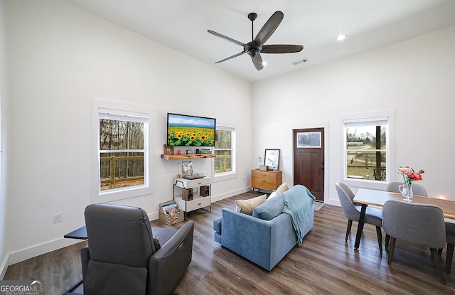 living room with dark wood-style floors, a ceiling fan, and a wealth of natural light