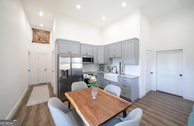 dining space featuring a towering ceiling, baseboards, dark wood-type flooring, and recessed lighting