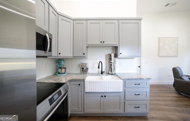 kitchen featuring visible vents, dark wood-type flooring, gray cabinets, stainless steel appliances, and a sink