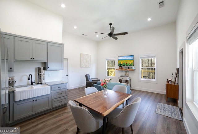 dining space featuring a towering ceiling, baseboards, visible vents, and dark wood-type flooring