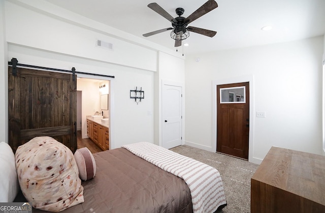 bedroom with a barn door, visible vents, carpet floors, a sink, and recessed lighting