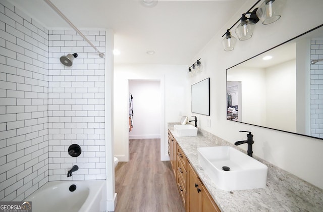 bathroom with double vanity, wood finished floors, tub / shower combination, and a sink