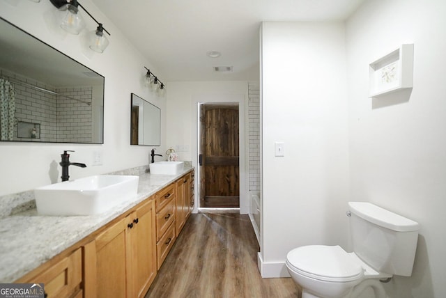 bathroom with double vanity, wood finished floors, a sink, and toilet