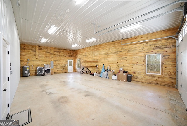 garage featuring washer and dryer, water heater, and wooden walls