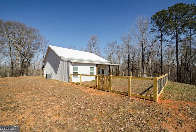 view of property exterior featuring a gate, fence, and central AC