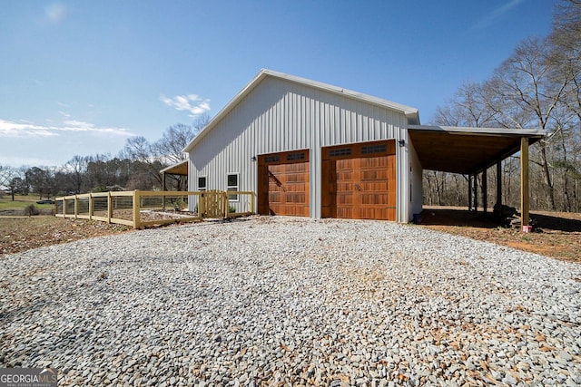 exterior space with an outbuilding, a carport, gravel driveway, and fence