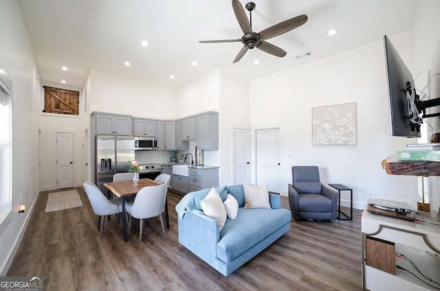 living room featuring baseboards, visible vents, dark wood finished floors, a towering ceiling, and recessed lighting