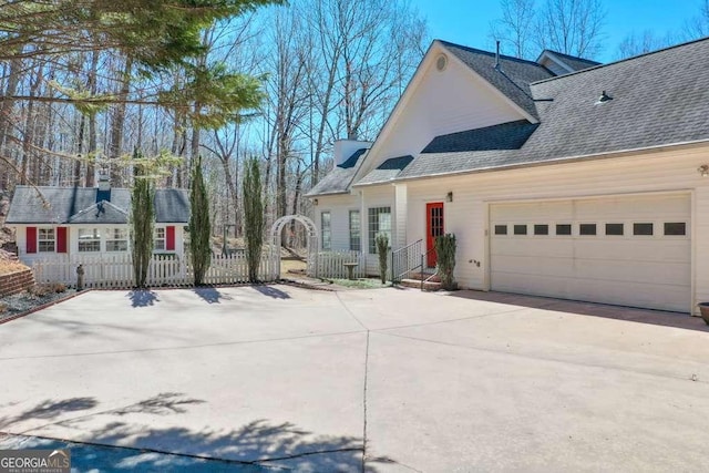 view of side of home with a garage, fence, concrete driveway, and roof with shingles