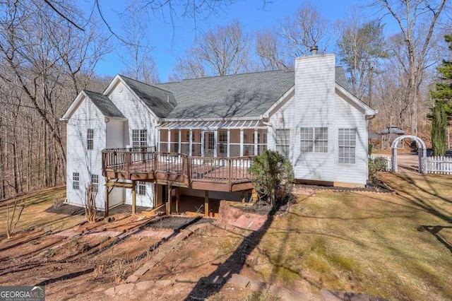 back of house featuring a chimney, a wooden deck, and a lawn