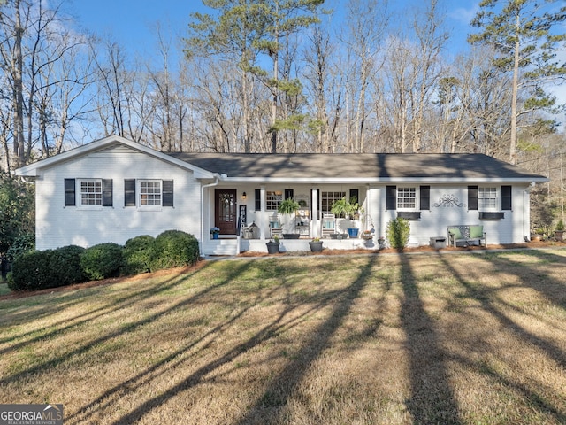 view of front of house with brick siding, a porch, and a front lawn