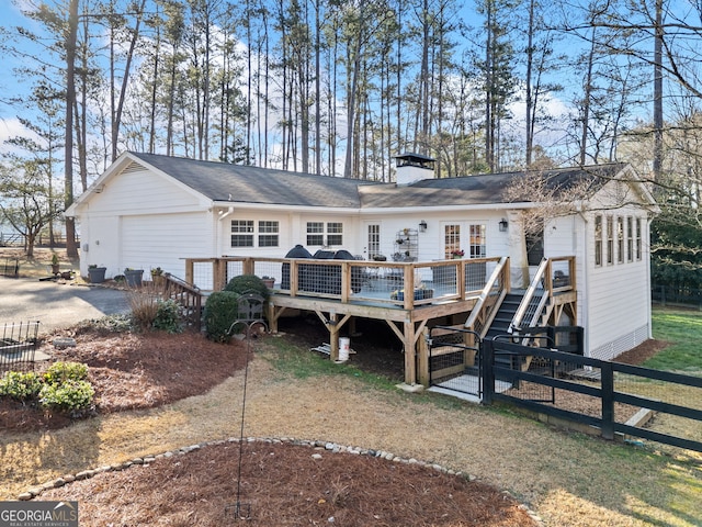 back of house with a chimney, a wooden deck, a garage, and fence