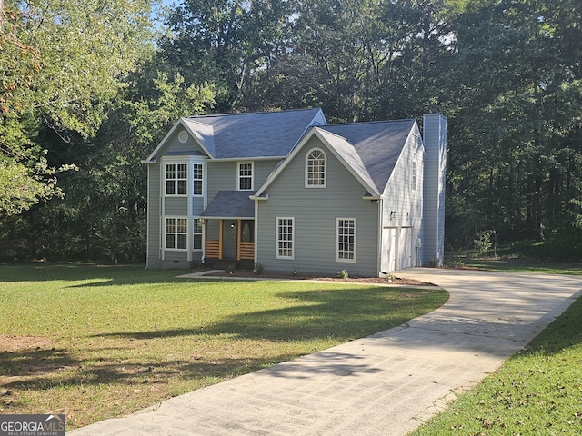 view of front of home with concrete driveway, crawl space, a forest view, a chimney, and a front yard