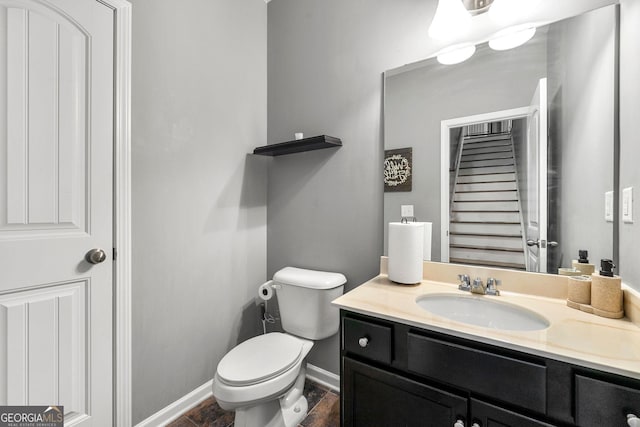 half bathroom featuring baseboards, vanity, and toilet