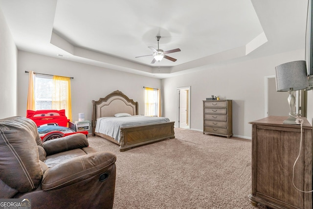 bedroom featuring baseboards, visible vents, ceiling fan, a tray ceiling, and carpet flooring