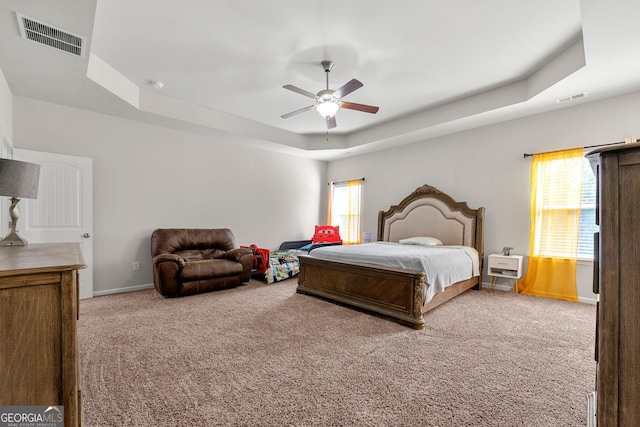 bedroom with carpet flooring, a raised ceiling, visible vents, and baseboards