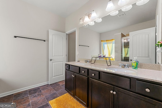 bathroom featuring a stall shower, visible vents, a sink, and baseboards