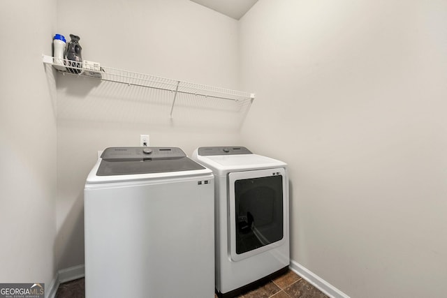 clothes washing area with laundry area, baseboards, and washer and clothes dryer