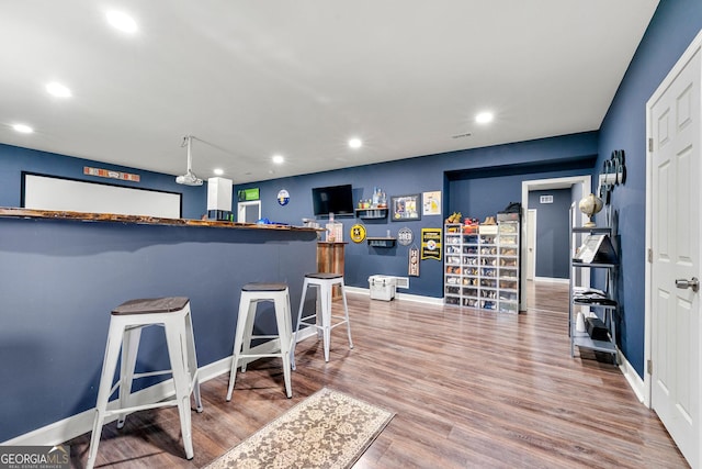 kitchen with baseboards, a breakfast bar, wood finished floors, and recessed lighting