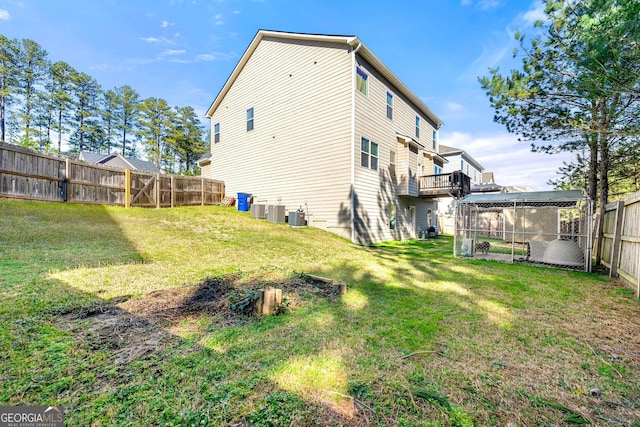 rear view of property with central AC unit, a lawn, and a fenced backyard