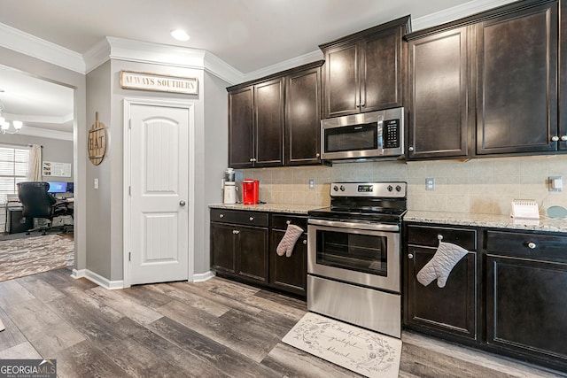 kitchen featuring light wood-type flooring, appliances with stainless steel finishes, backsplash, and ornamental molding