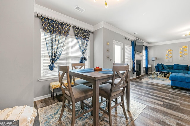 dining area featuring ornamental molding, a healthy amount of sunlight, visible vents, and wood finished floors