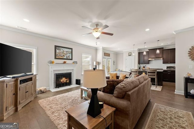 living area with recessed lighting, dark wood-style flooring, a ceiling fan, visible vents, and crown molding