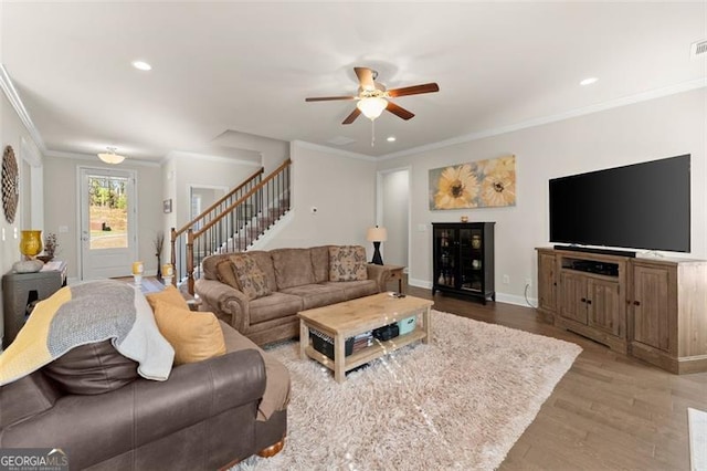 living area featuring baseboards, ornamental molding, wood finished floors, stairs, and recessed lighting