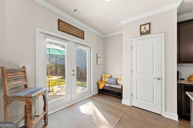 doorway to outside featuring visible vents, baseboards, ornamental molding, french doors, and light wood-type flooring