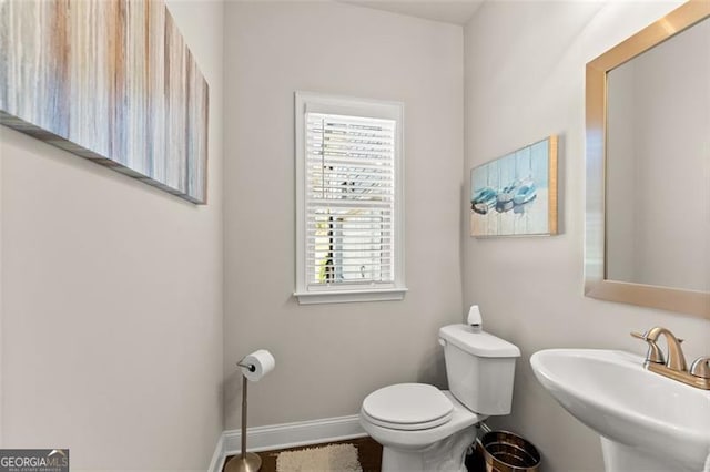 bathroom with a sink, toilet, and baseboards