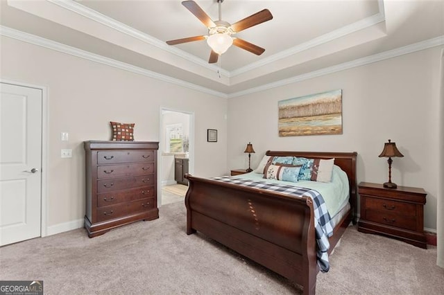 bedroom with a tray ceiling, crown molding, light carpet, connected bathroom, and ceiling fan