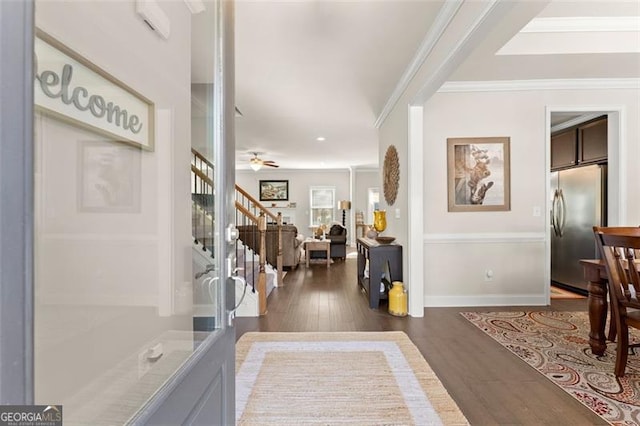 foyer entrance with crown molding, stairway, dark wood-type flooring, a ceiling fan, and baseboards