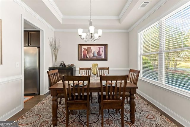 dining area with a chandelier, a tray ceiling, visible vents, and crown molding