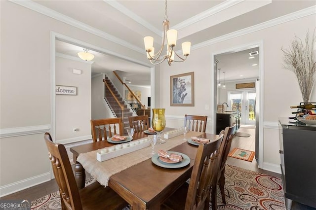 dining room featuring a notable chandelier, stairway, ornamental molding, wood finished floors, and baseboards