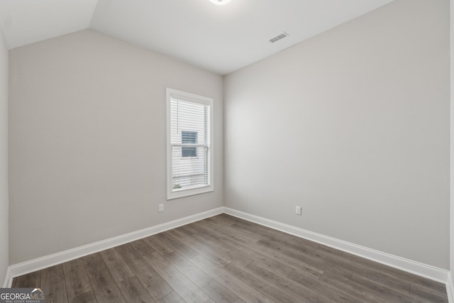 empty room with vaulted ceiling, dark wood finished floors, visible vents, and baseboards