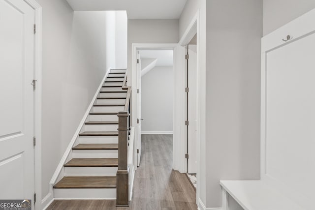 stairway with wood finished floors and baseboards