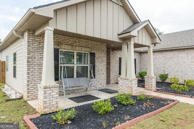 entrance to property featuring board and batten siding, covered porch, and brick siding