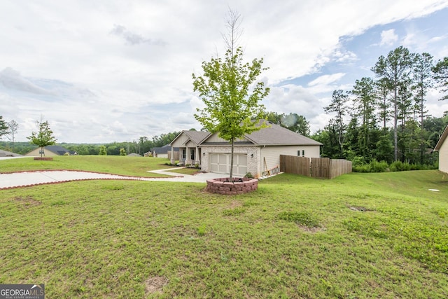 view of yard with concrete driveway, an attached garage, and fence