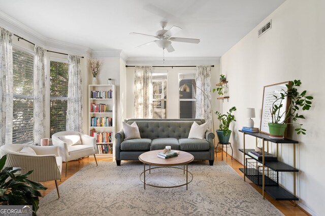 living room featuring visible vents, ornamental molding, ceiling fan, and wood finished floors