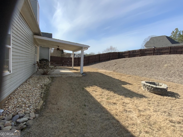 view of yard with a ceiling fan, an outdoor fire pit, a patio area, and a fenced backyard