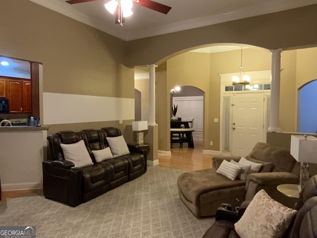 living room featuring a ceiling fan, arched walkways, crown molding, and ornate columns