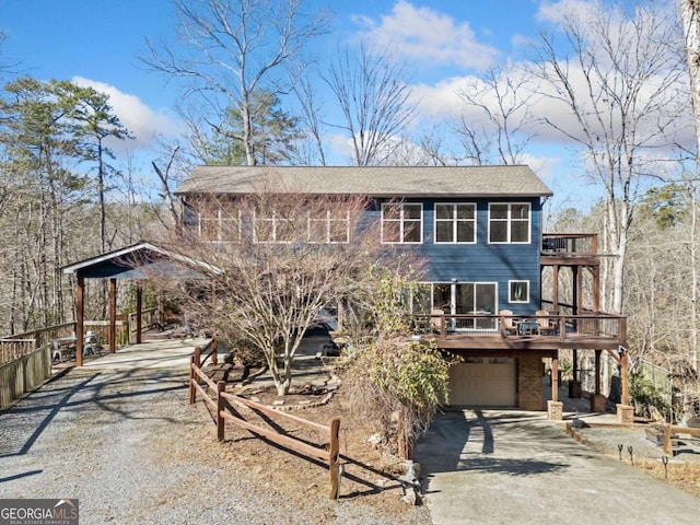 view of front facade with an attached garage, a balcony, brick siding, a wooden deck, and gravel driveway