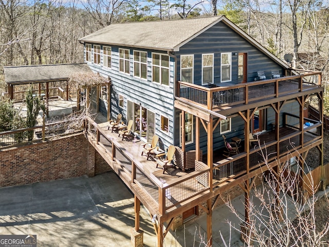 rear view of house with a deck and roof with shingles