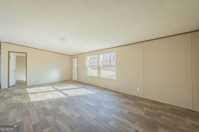 unfurnished room with crown molding, a textured ceiling, and wood finished floors