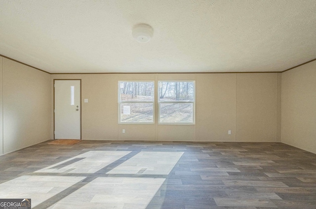 spare room with a textured ceiling, wood finished floors, and crown molding