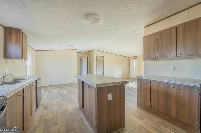 kitchen with lofted ceiling, a kitchen island, appliances with stainless steel finishes, light wood-type flooring, and a sink