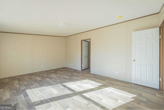 spare room with wood finished floors and crown molding