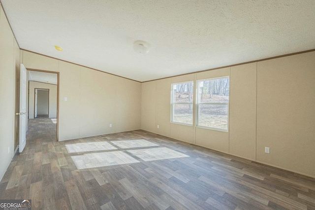 unfurnished room featuring crown molding, a textured ceiling, and wood finished floors